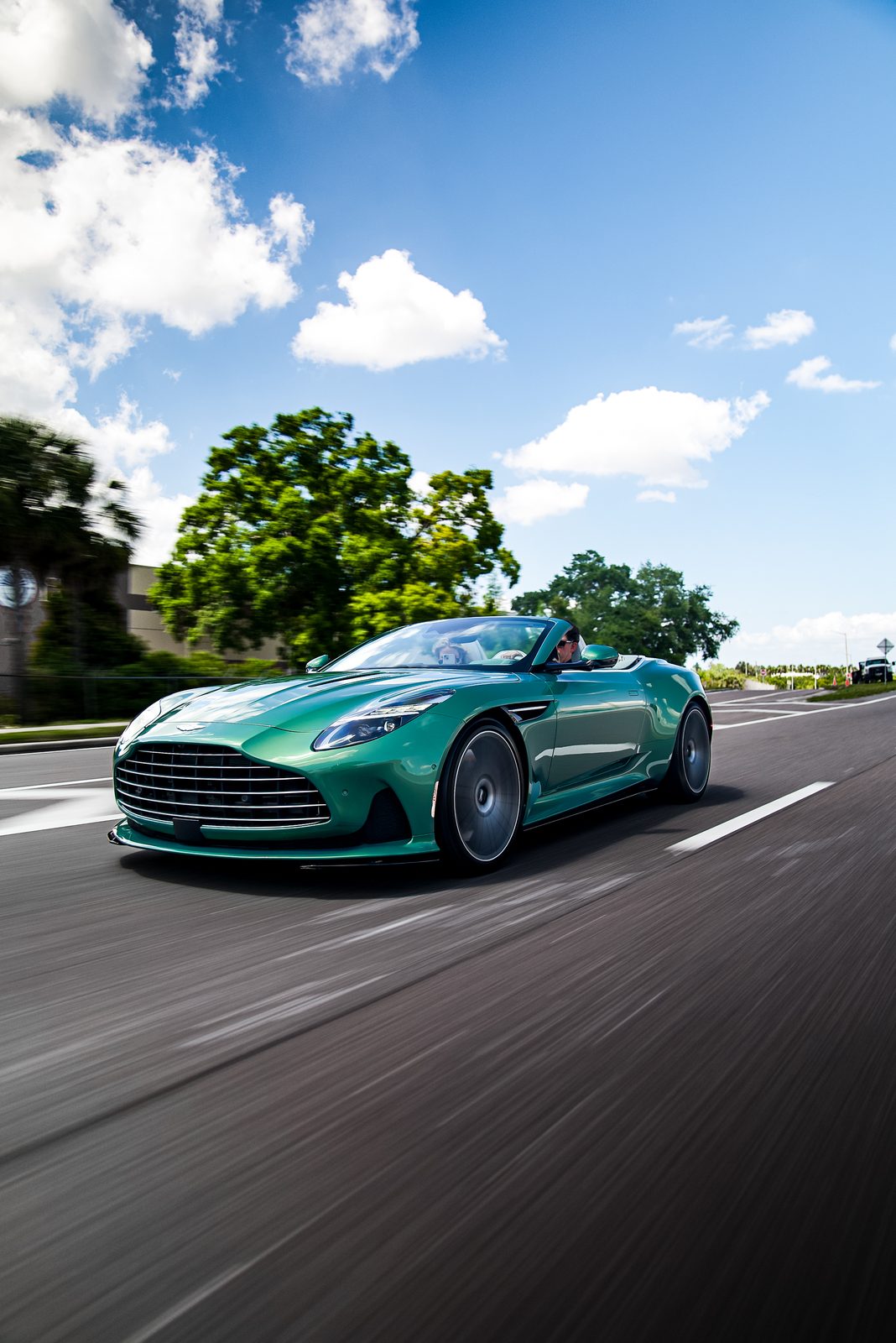 Aston Martin DB12 Volante driving on a sunny road
