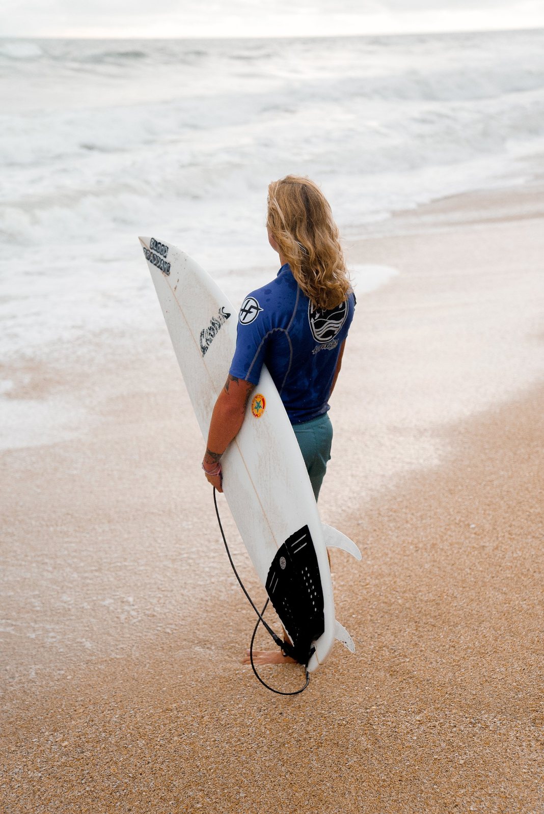 Surfer holding a board at the water's edge