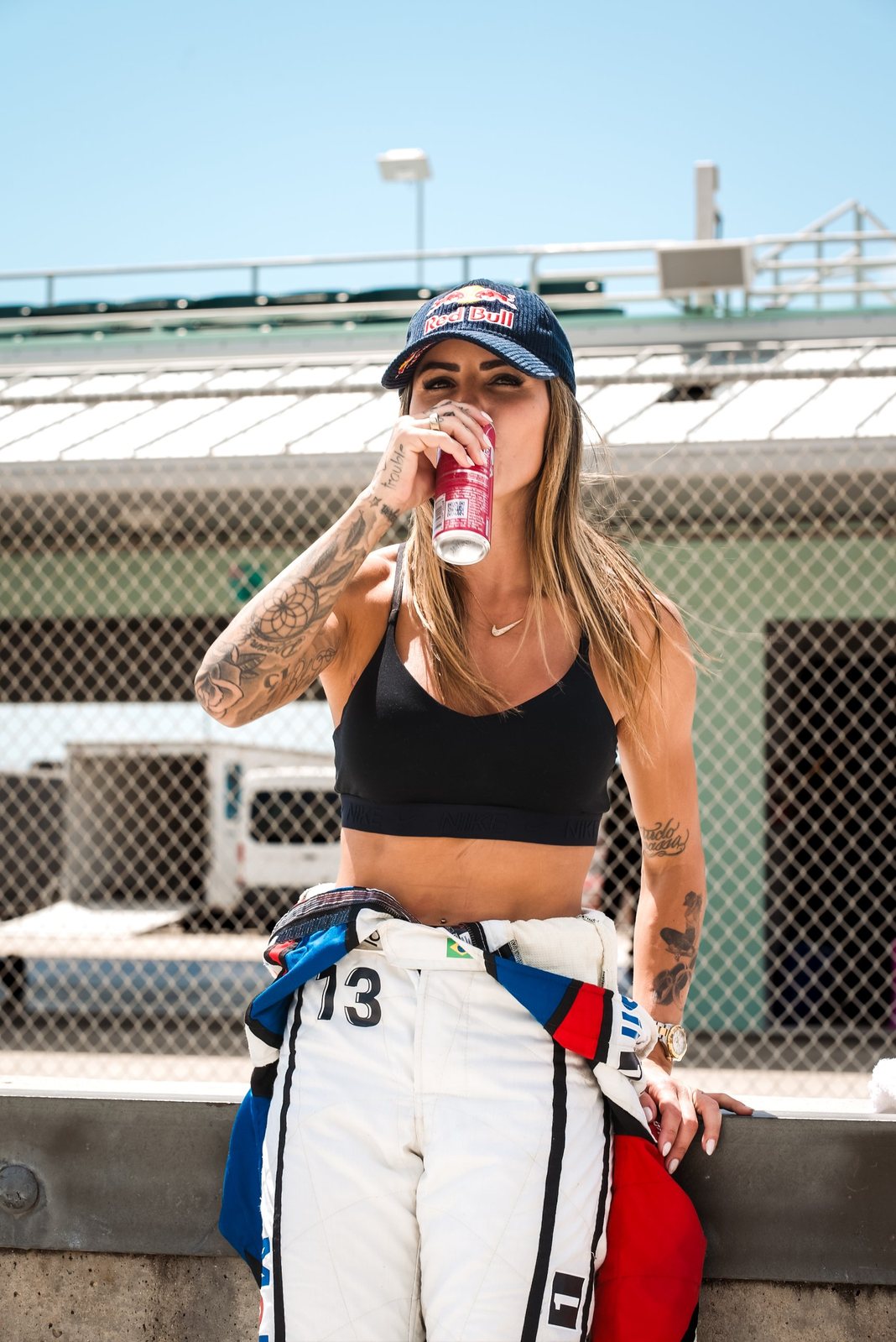 Driver in a Red Bull cap drinking a Red Bull at the track