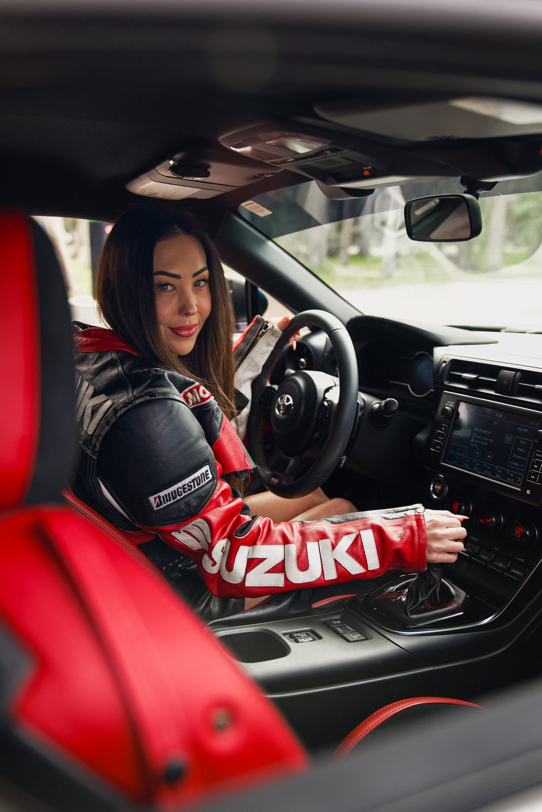 Woman in a Suzuki leather jacket behind the wheel