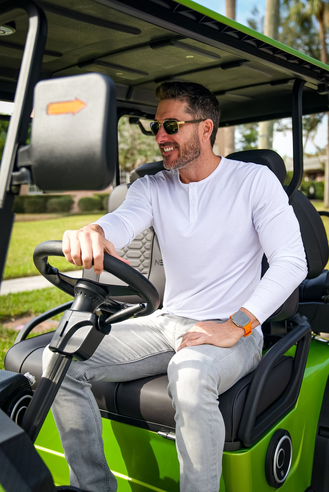 Man in sunglasses smiling in a green golf cart