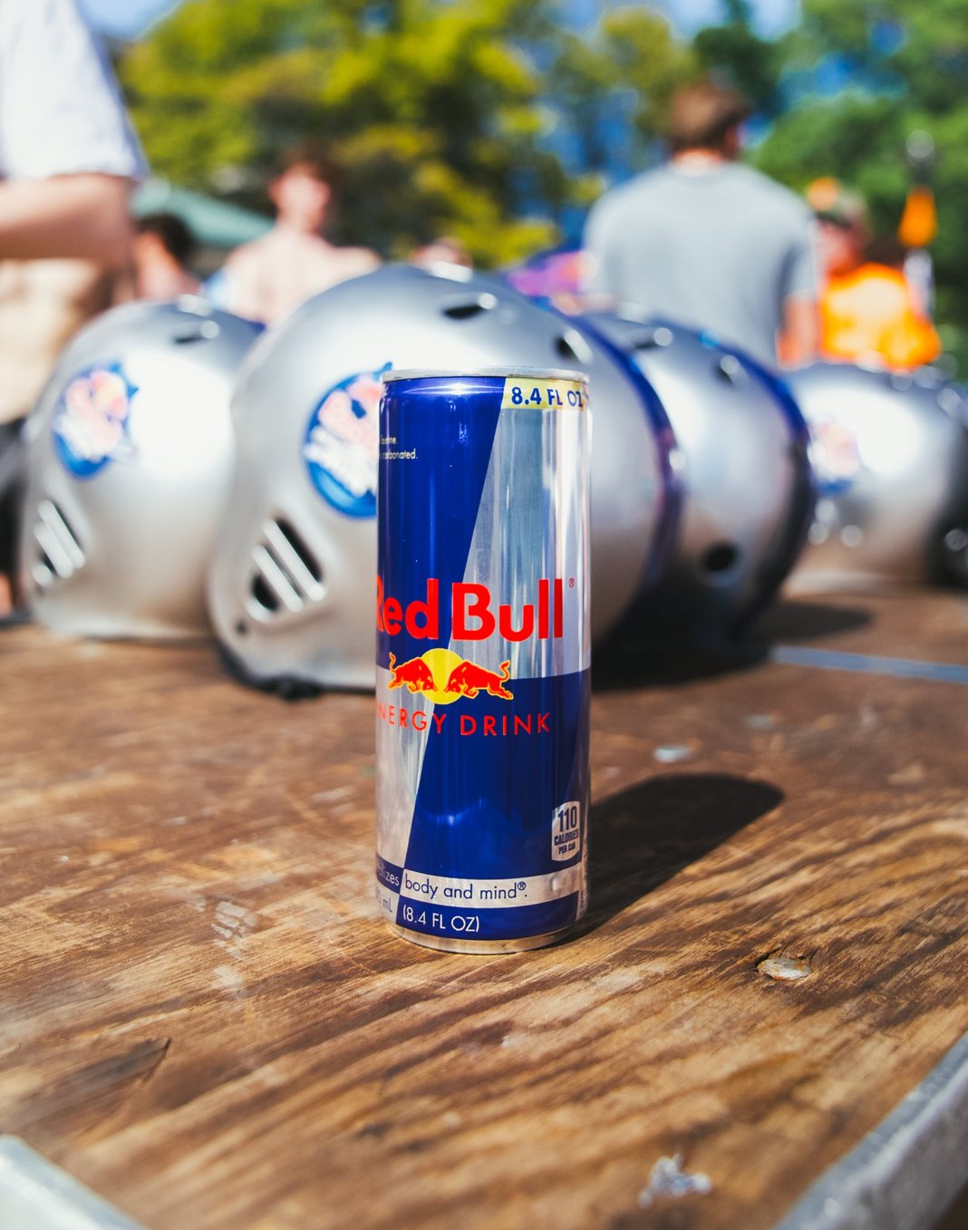Red Bull can on a table in front of a row of branded helmets at an event