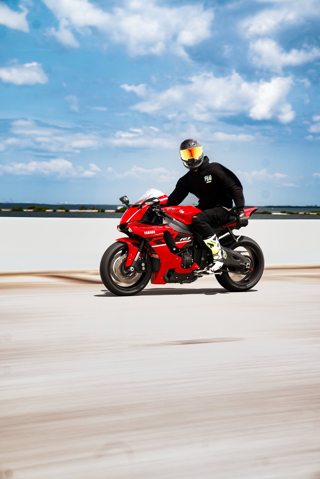 Rider on a red Yamaha R1 cruising across a waterfront causeway