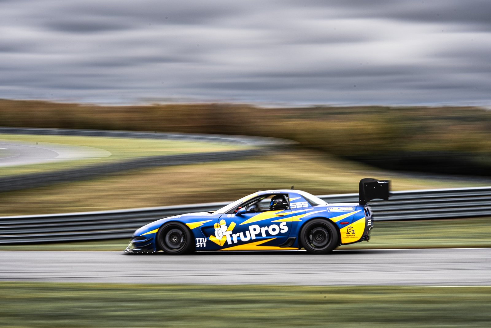 Blue and yellow TruPros Corvette race car panning shot on track