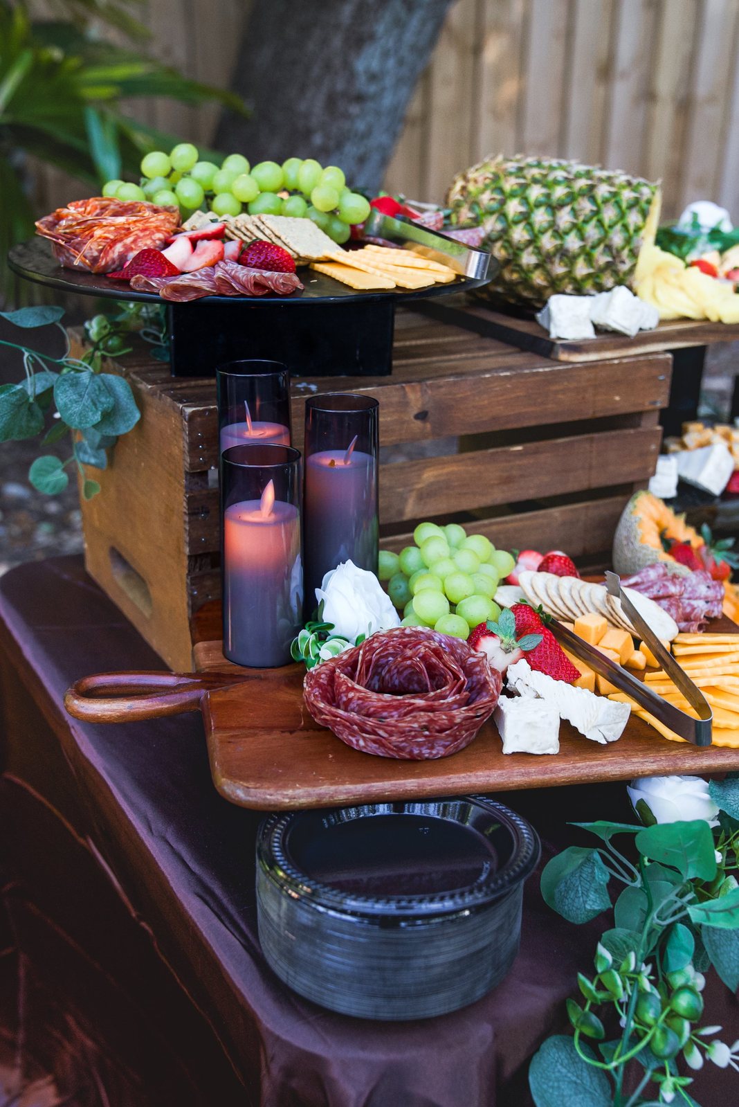 Charcuterie and fruit grazing table with candles at an outdoor event