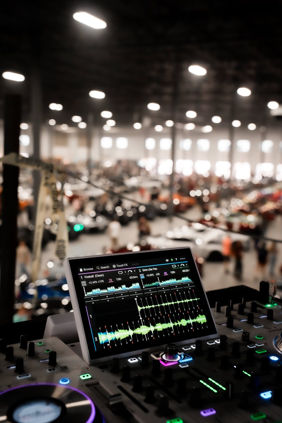 DJ deck overlooking an indoor car show crowd