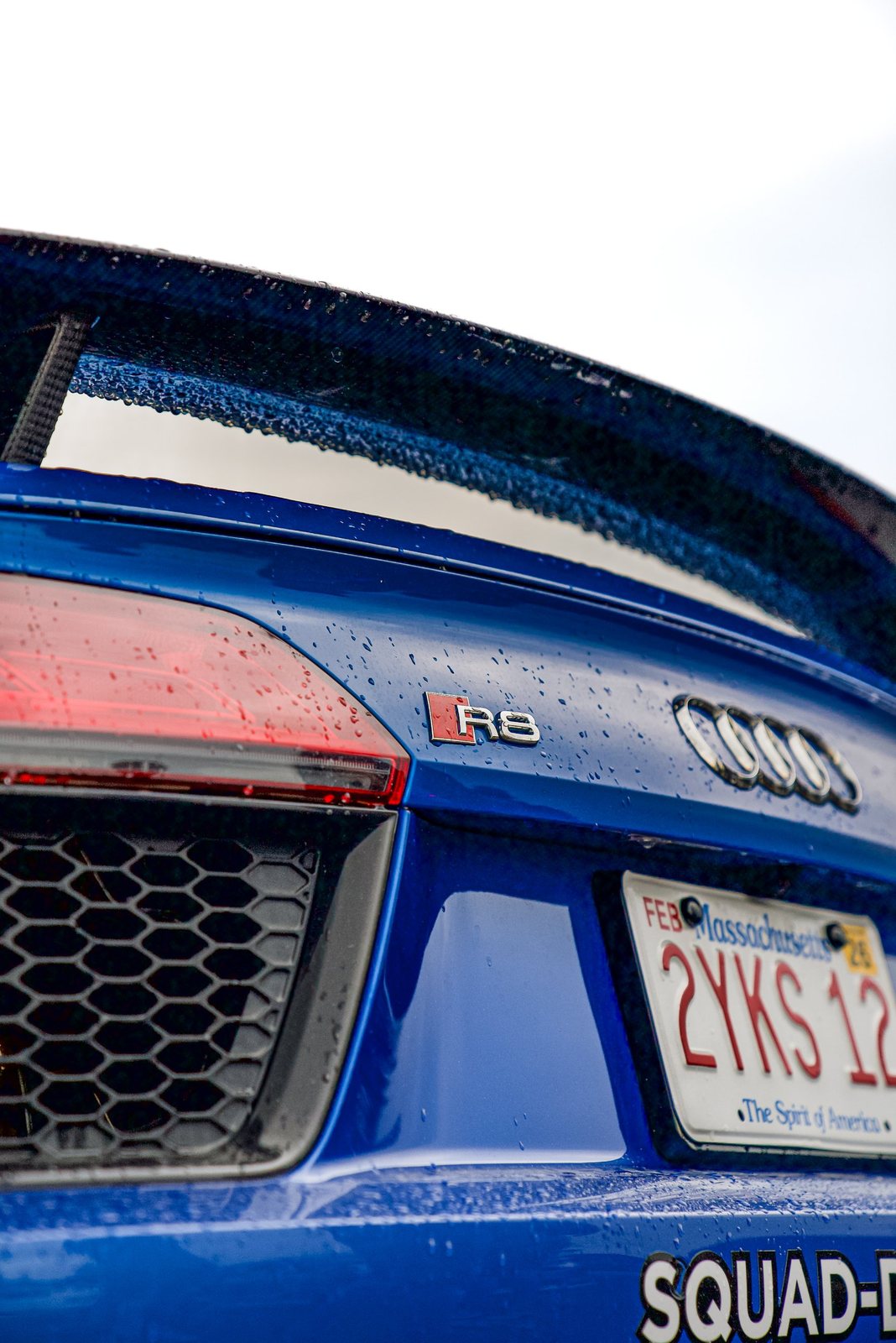 Rain-beaded rear wing and R8 badge on a blue Audi R8