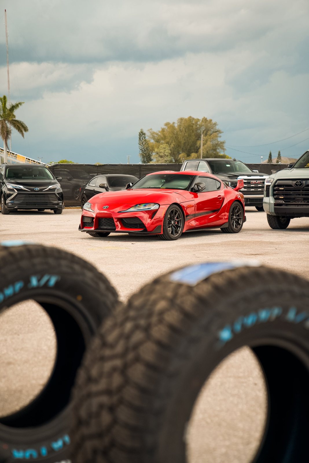 Red Toyota Supra framed between off-road tires