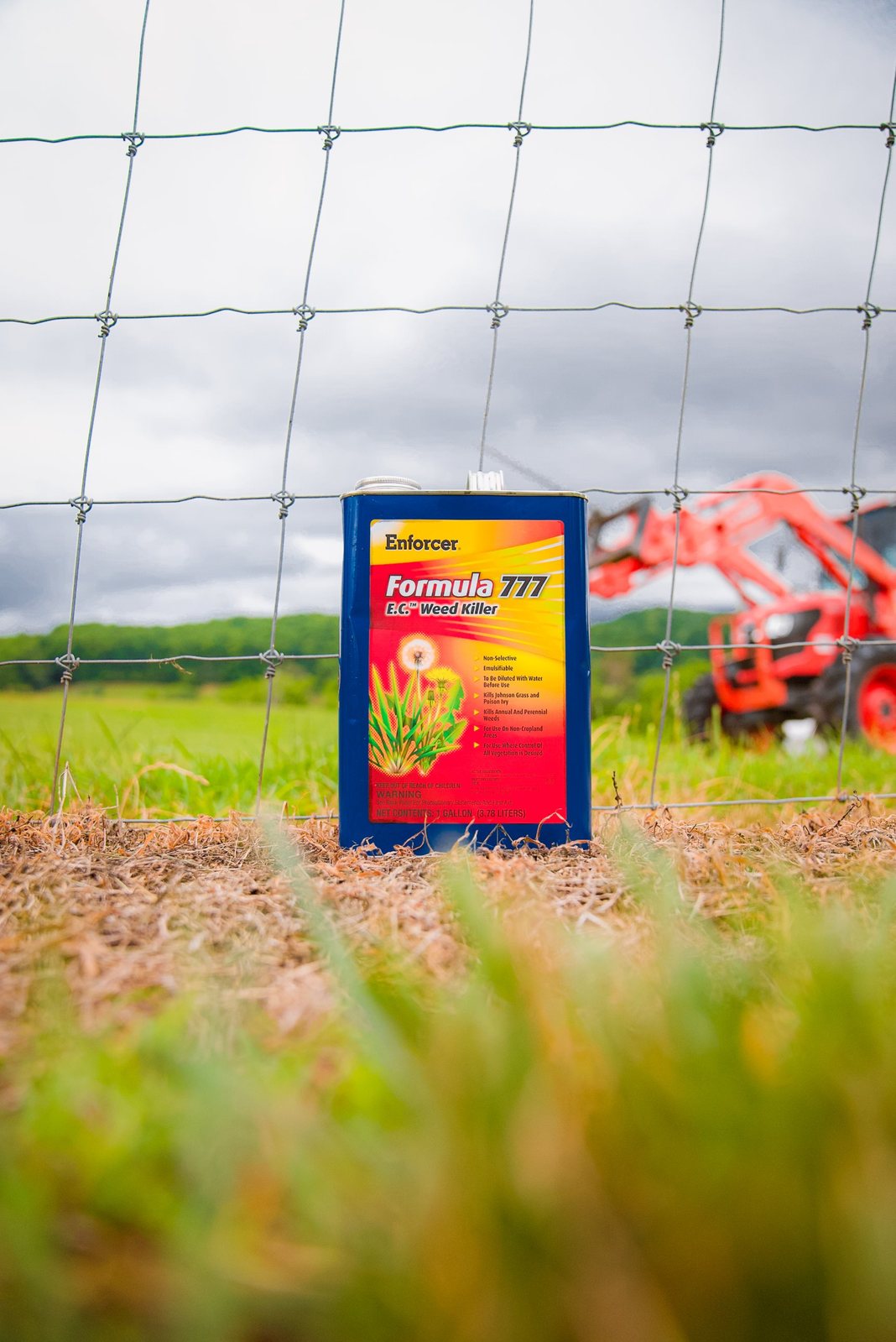 Enforcer Formula 777 can at a farm fence with a tractor behind