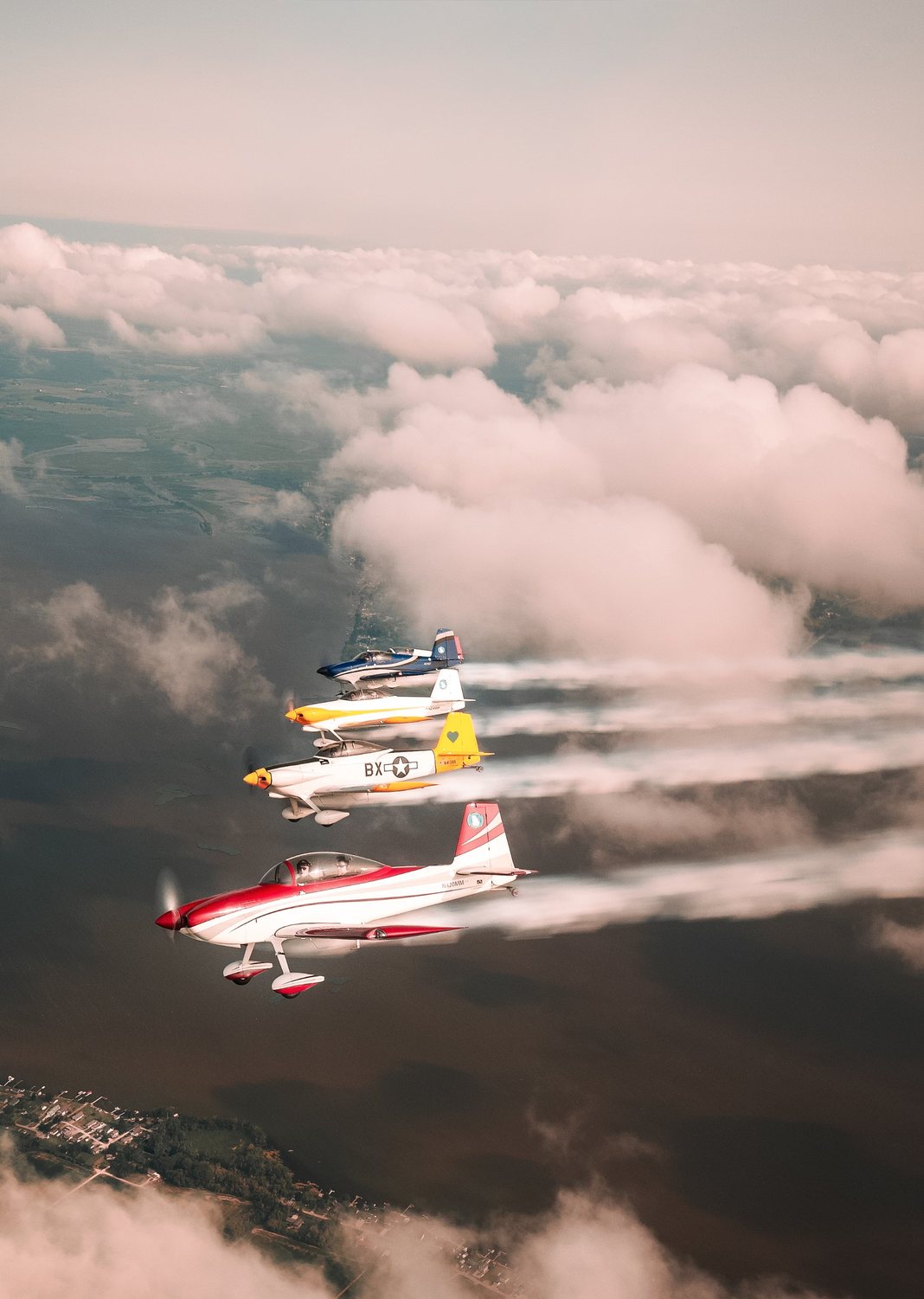 Four aerobatic planes flying in formation above the clouds